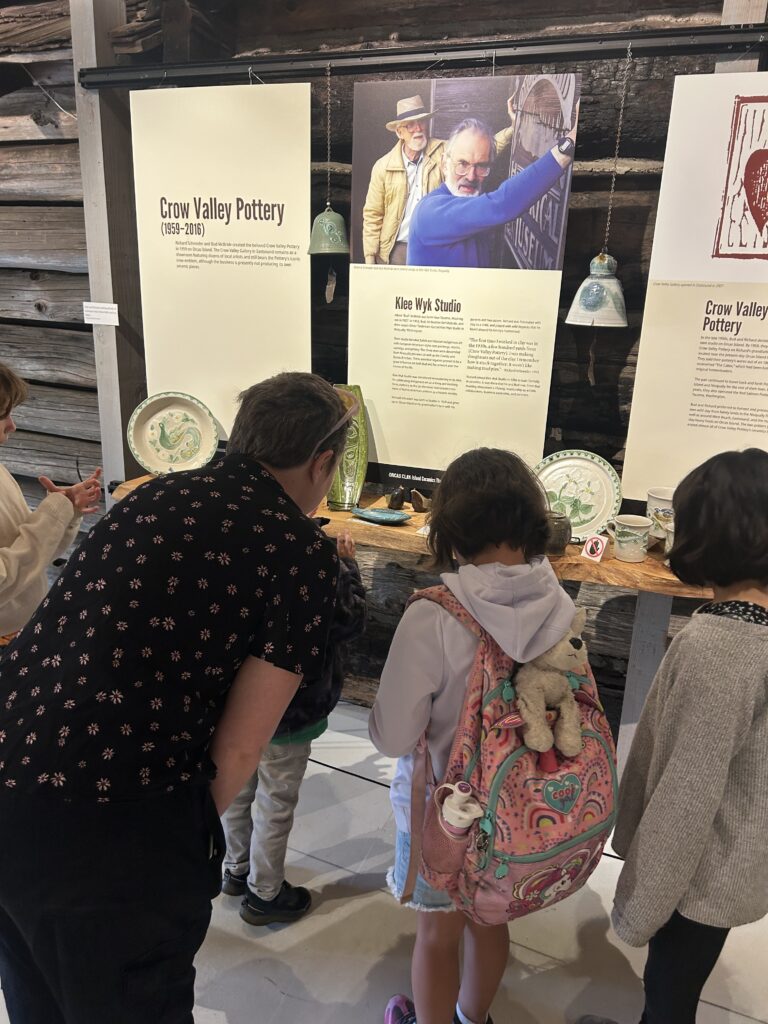 Staff member Parker and two students lean in to view an exhibit.