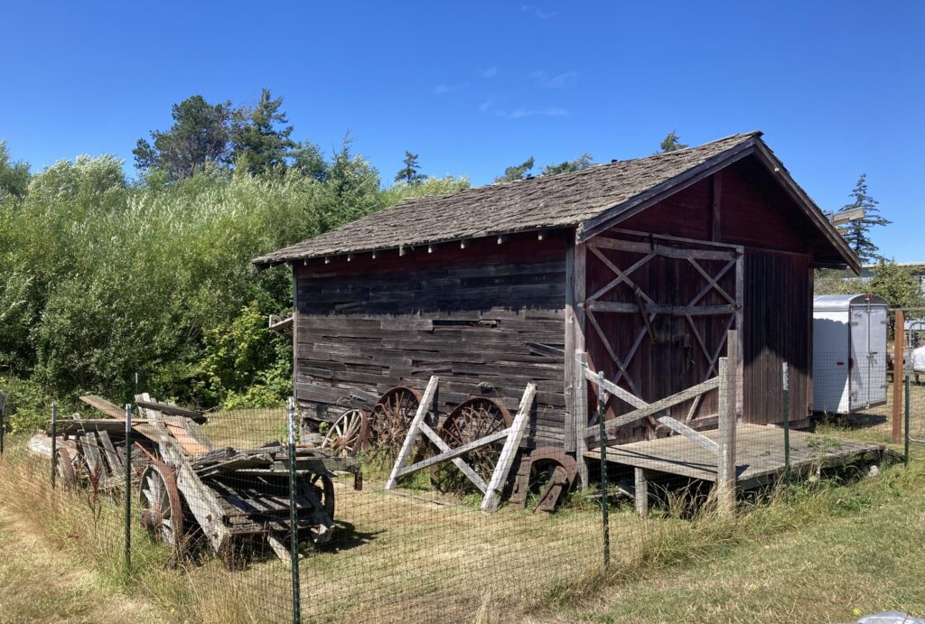 Fire Barn viewed from the lefthand side with agricultural equipment in fireground. Photo taken 2026.